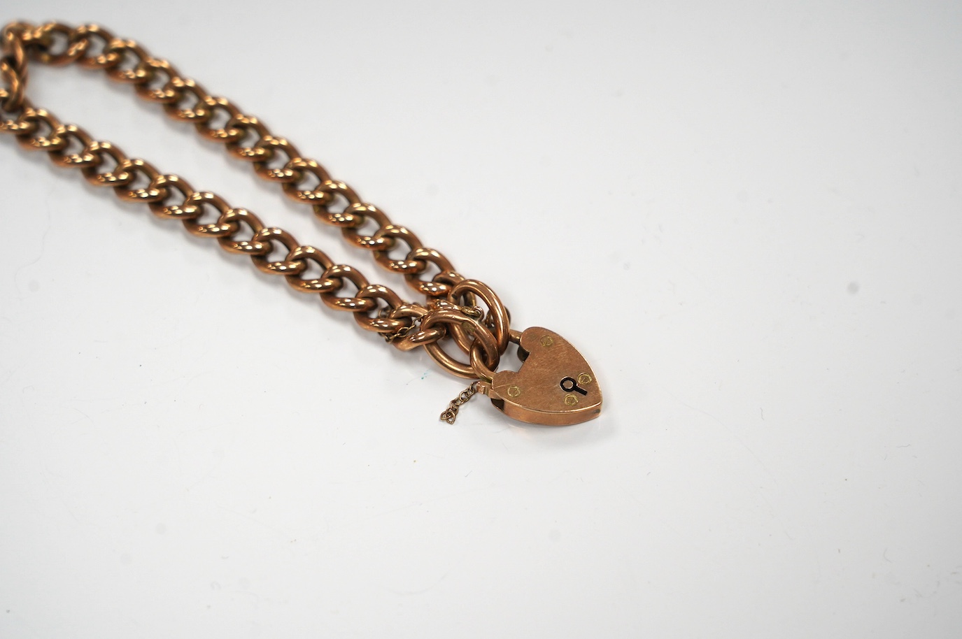 An Edwardian 9ct gold curb link bracelet, with heart shaped padlock clasp, 17cm, 10 grams. Condition - fair to good